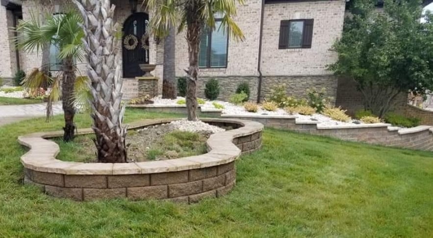 Modern brick home with curved stone landscape beds around palm tree