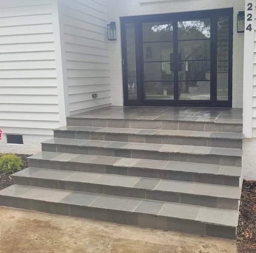 Concrete steps leading up to a modern home entrance with dark framed glass doors