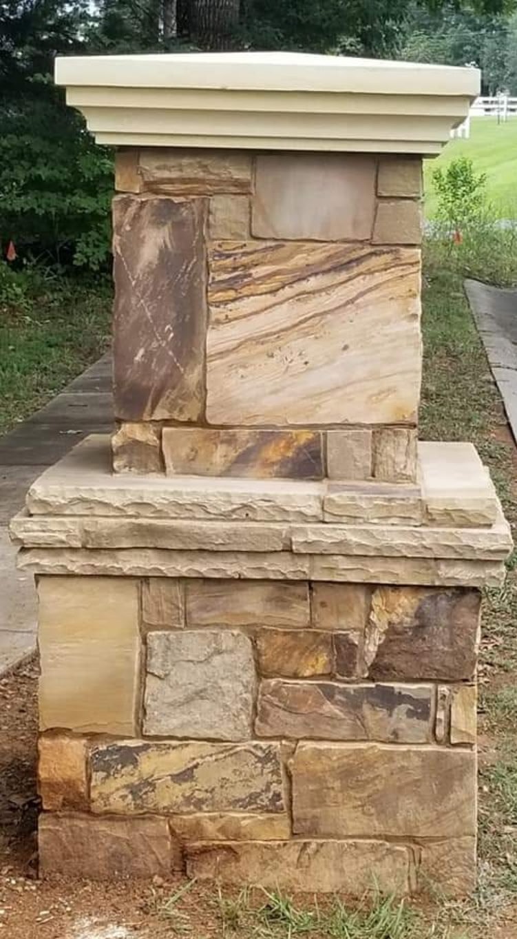 Wooden mailbox mounted on a stone and brick post in a residential yard